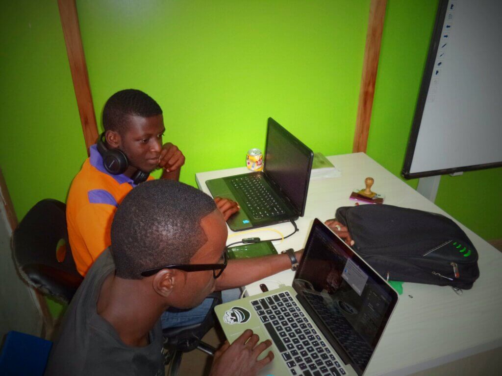 Two young boys working at laptops at work