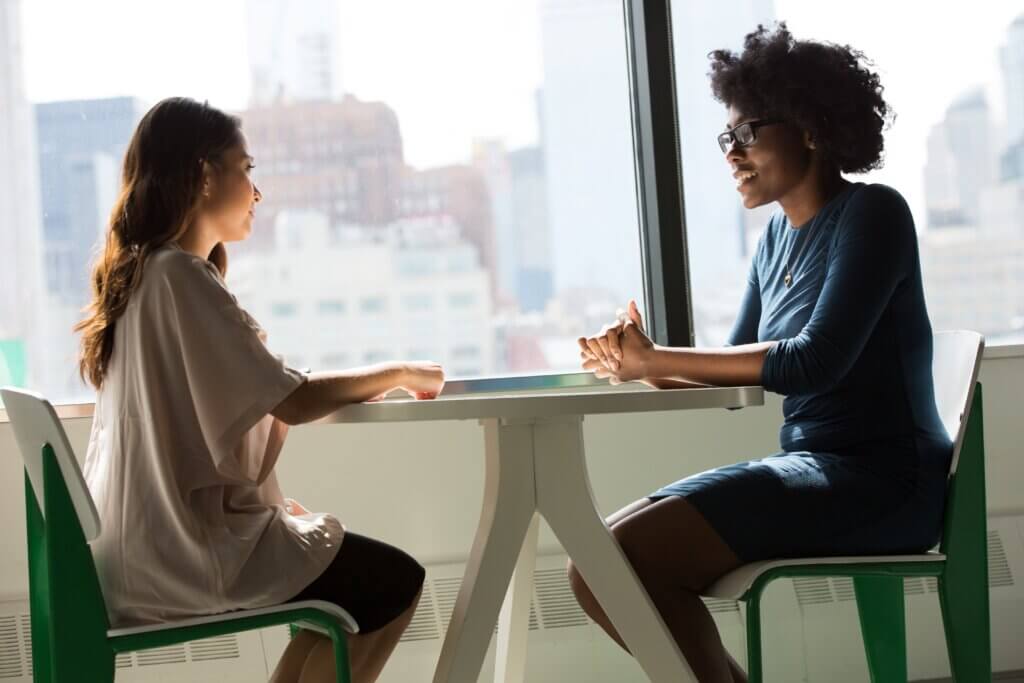 Two women sitting at table discussing Maternity Leave.